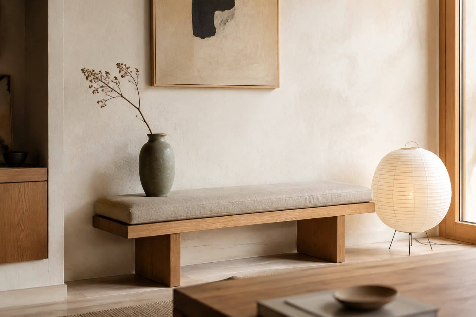 A Japandi living corner with a low oak bench, a paper floor lamp, a ceramic vase and very little else